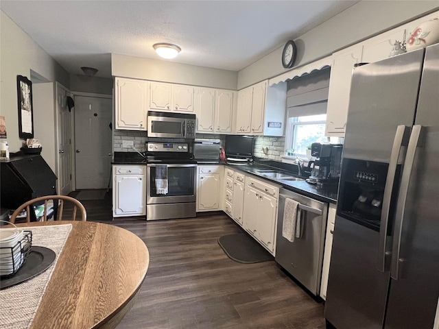 313 E 29th St S, Newton, IA 50208 - kitchen with stainless steel appliances, a sink, dark countertops, and white cabinets