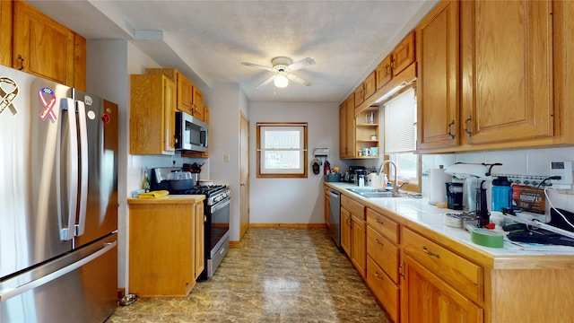 6465 NW 56th St, Johnston, IA 50131 - kitchen featuring appliances with stainless steel finishes, a sink, a ceiling fan, baseboards, and brown cabinets