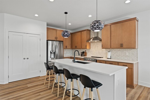 110 Bailey Cir, Waukee, IA 50263 - kitchen with stainless steel appliances, wall chimney exhaust hood, a sink, light wood-style flooring, and recessed lighting
