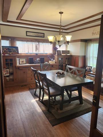 230 Grant St, Murray, IA 50174 - dining area featuring wainscoting, wood finished floors, a raised ceiling, and crown molding