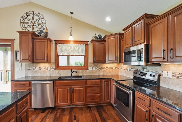 4014 NE Bellagio Cir, Ankeny, IA 50021 - kitchen with stainless steel appliances, a sink, lofted ceiling, brown cabinetry, and dark wood finished floors