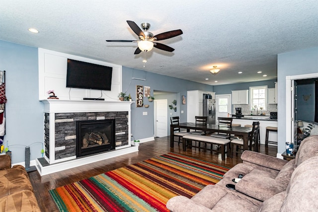 2212 228th Pl, Ames, IA 50014 - living area featuring a ceiling fan, a textured ceiling, a fireplace, baseboards, and wood finished floors
