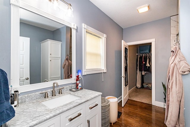 2212 228th Pl, Ames, IA 50014 - bathroom with wood finished floors, vanity, a spacious closet, and baseboards