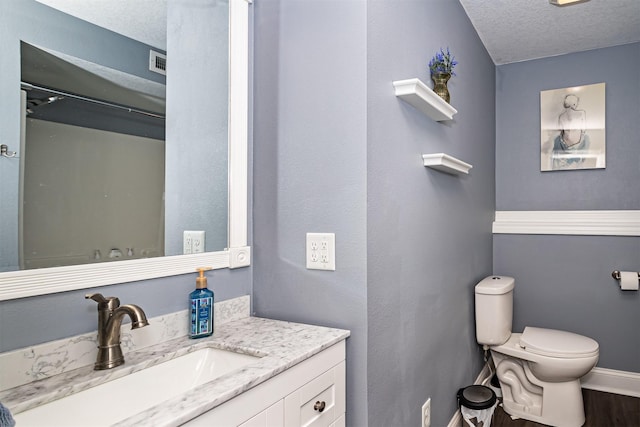 2212 228th Pl, Ames, IA 50014 - bathroom with a textured ceiling, toilet, vanity, baseboards, and wood finished floors