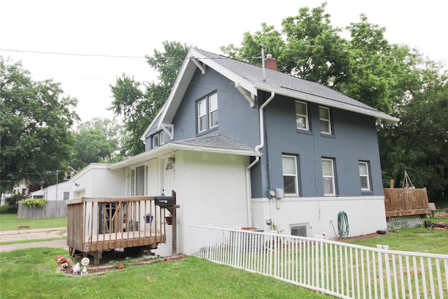 1035 65th St, Windsor Heights, IA 50324 - view of side of property featuring a wooden deck, a chimney, a shingled roof, brick siding, and stucco siding