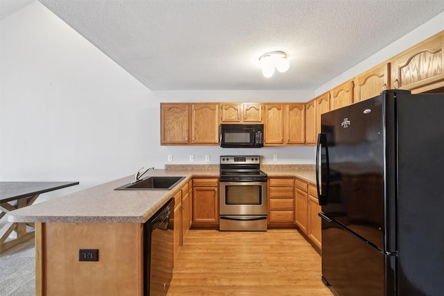 4425 Mills Civic Pkwy Unit 803, West Des Moines, IA 50265 - kitchen with black appliances, a sink, light wood finished floors, a peninsula, and a textured ceiling