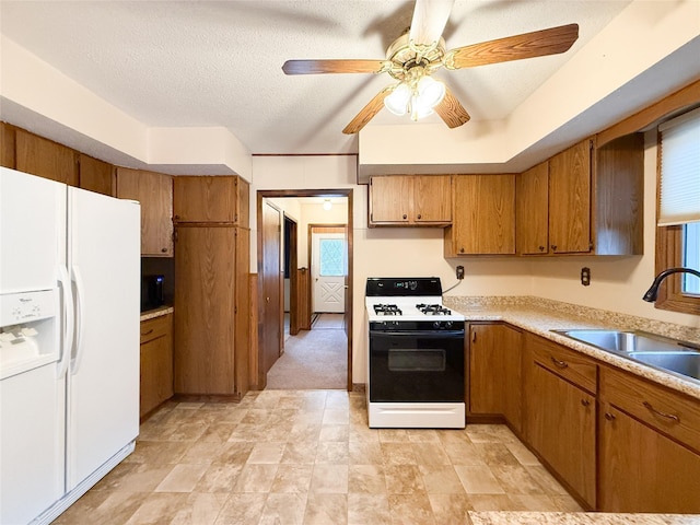 1545 5th St, Boone, IA 50036 - kitchen featuring gas range oven, white refrigerator with ice dispenser, brown cabinets, a sink, and light countertops