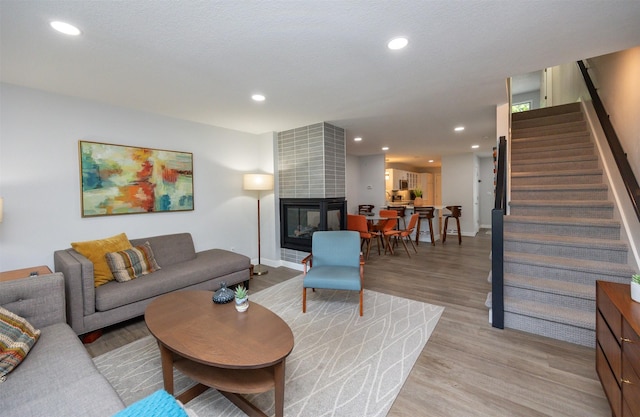 6196 Terrace Dr Unit 2, Johnston, IA 50131 - living room featuring stairway, light wood-style floors, a tiled fireplace, recessed lighting, and baseboards