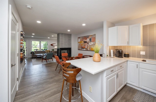 6196 Terrace Dr Unit 2, Johnston, IA 50131 - kitchen featuring a breakfast bar area, open floor plan, a peninsula, white cabinetry, and wood finished floors