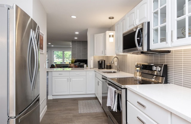 6196 Terrace Dr Unit 2, Johnston, IA 50131 - kitchen with stainless steel appliances, glass insert cabinets, dark wood-style flooring, white cabinetry, and tasteful backsplash