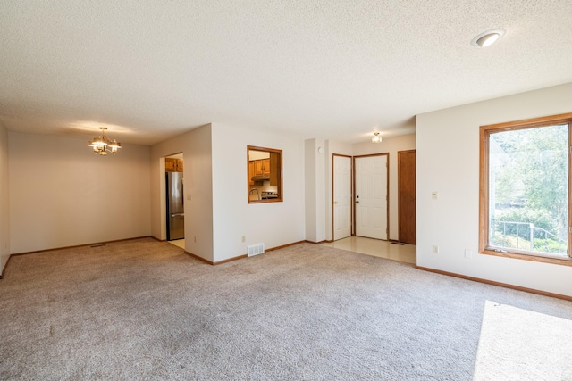 3916 92nd Dr, Urbandale, IA 50322 - unfurnished room featuring a chandelier, light colored carpet, and a textured ceiling
