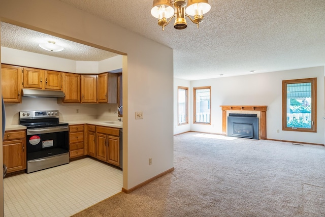 3916 92nd Dr, Urbandale, IA 50322 - kitchen with stainless steel range with electric cooktop, under cabinet range hood, a textured ceiling, light colored carpet, and a glass covered fireplace