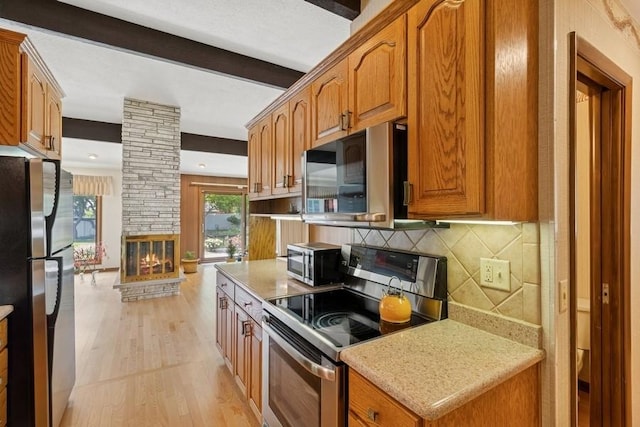 2110 Ashmore Dr, Ames, IA 50014 - kitchen featuring stainless steel appliances, tasteful backsplash, light wood-type flooring, brown cabinets, and beamed ceiling