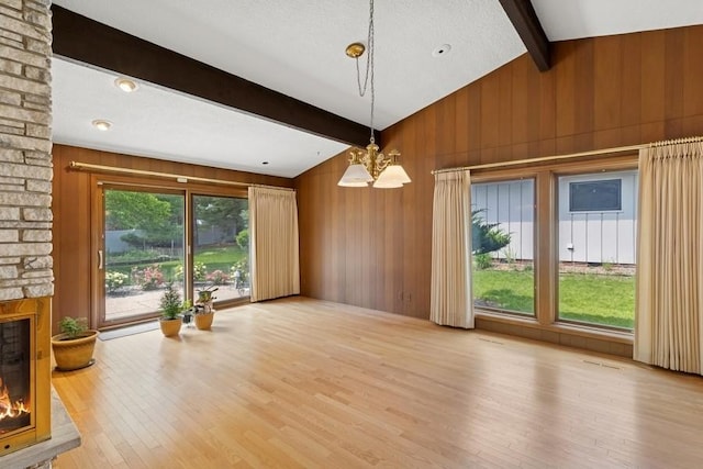 2110 Ashmore Dr, Ames, IA 50014 - unfurnished dining area featuring wood finished floors, a stone fireplace, wooden walls, and a chandelier