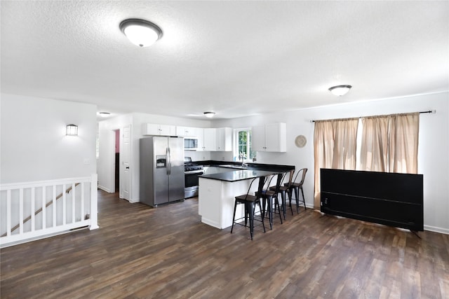 1908 E Walnut St, Des Moines, IA 50316 - kitchen with appliances with stainless steel finishes, dark countertops, a breakfast bar, a peninsula, and white cabinets