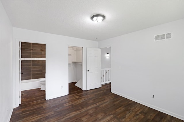 1908 E Walnut St, Des Moines, IA 50316 - unfurnished bedroom with wood finished floors, baseboards, ensuite bath, a closet, and a walk in closet