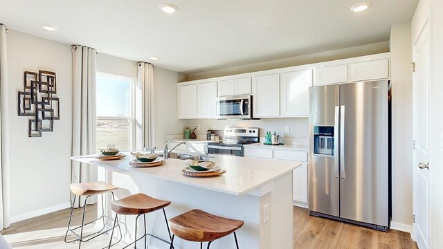 450 Meadows Ct, Polk City, IA 50226 - kitchen featuring appliances with stainless steel finishes, light wood-type flooring, a sink, an island with sink, and a breakfast bar area