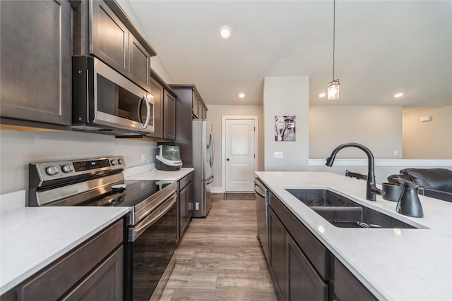 602 NE 57th St, Ankeny, IA 50021 - kitchen with stainless steel appliances, a sink, dark brown cabinets, light countertops, and light wood-style floors