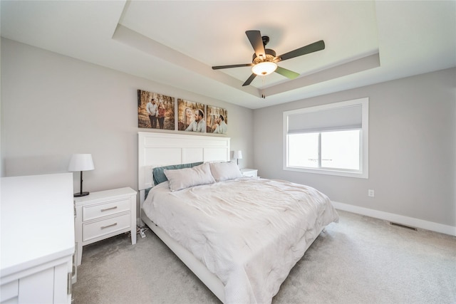 602 NE 57th St, Ankeny, IA 50021 - bedroom featuring light colored carpet, a tray ceiling, baseboards, and ceiling fan