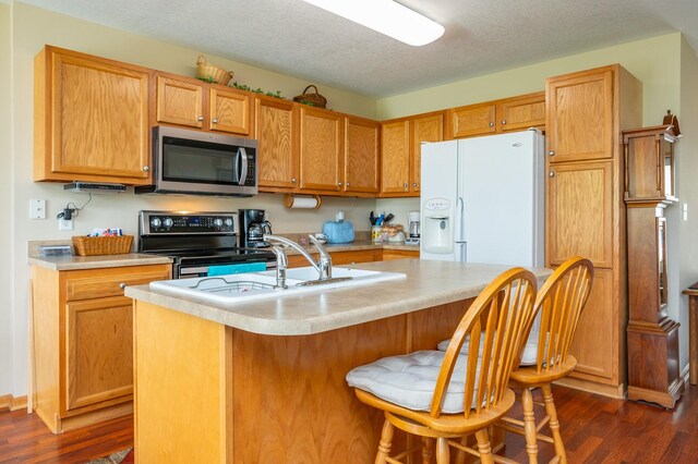 168 SE Sweetgrass Ln, Pleasant Hill, IA 50327 - kitchen featuring stainless steel appliances, dark wood-type flooring, light countertops, an island with sink, and a textured ceiling