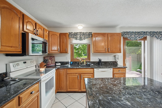 4623 62nd St, Urbandale, IA 50322 - kitchen with white appliances, dark stone countertops, a textured ceiling, brown cabinetry, and light tile patterned floors