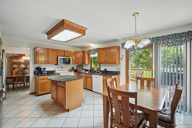 4623 62nd St, Urbandale, IA 50322 - kitchen with appliances with stainless steel finishes, a chandelier, a center island, a textured ceiling, and brown cabinetry