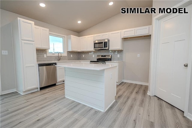 25088 Bluebird Cir, Adel, IA 50003 - kitchen with stainless steel appliances, light wood-type flooring, white cabinetry, decorative backsplash, and lofted ceiling
