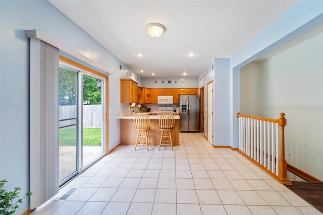 403 4th St NW, Altoona, IA 50009 - kitchen with stainless steel refrigerator with ice dispenser, white microwave, a peninsula, light countertops, and stove