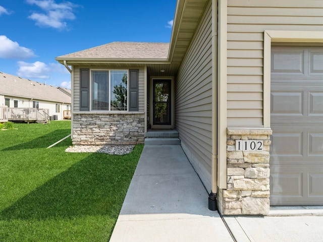 1102 NE 15th Ln, Ankeny, IA 50021 - view of exterior entry featuring stone siding, a garage, a yard, and a shingled roof