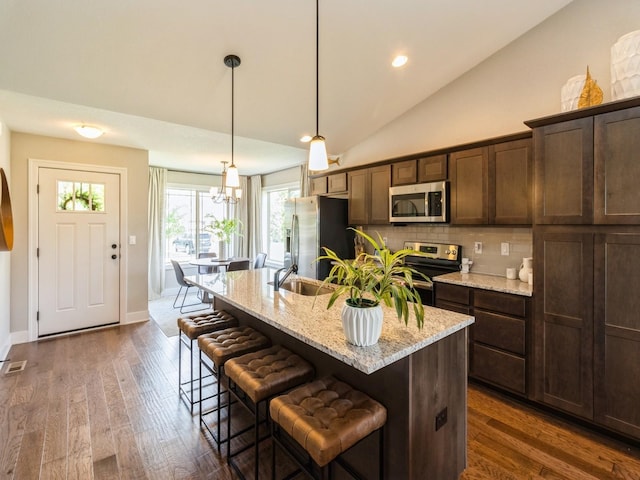 1102 NE 15th Ln, Ankeny, IA 50021 - kitchen featuring stainless steel appliances, dark wood-type flooring, a breakfast bar area, tasteful backsplash, and lofted ceiling
