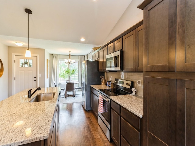 1102 NE 15th Ln, Ankeny, IA 50021 - kitchen featuring stainless steel appliances, vaulted ceiling, a chandelier, a center island with sink, and decorative backsplash
