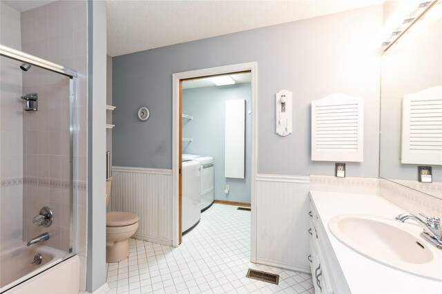 4922 Cedar Dr, West Des Moines, IA 50266 - bathroom featuring washing machine and clothes dryer, wainscoting, vanity, tile patterned flooring, and bath / shower combo with glass door