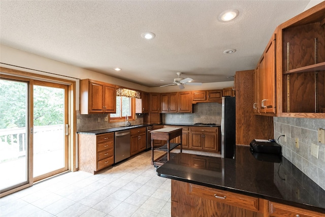4922 Cedar Dr, West Des Moines, IA 50266 - kitchen with appliances with stainless steel finishes, dark countertops, brown cabinetry, backsplash, and a textured ceiling
