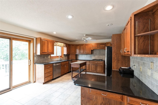 4922 Cedar Dr, West Des Moines, IA 50266 - kitchen featuring appliances with stainless steel finishes, brown cabinetry, backsplash, dark countertops, and a textured ceiling