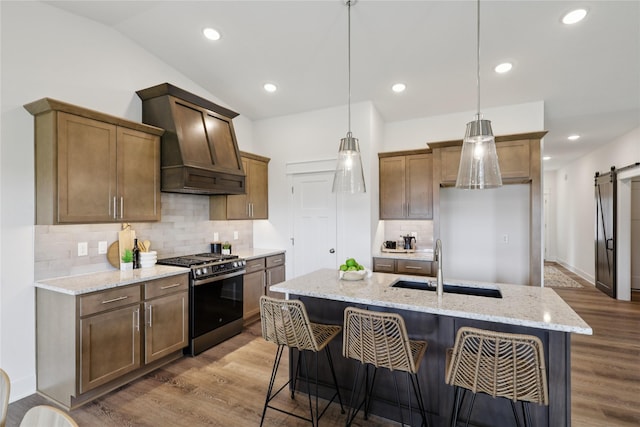 150 NW Hidden Knl, Waukee, IA 50263 - kitchen with gas stove, a barn door, custom exhaust hood, wood finished floors, and vaulted ceiling