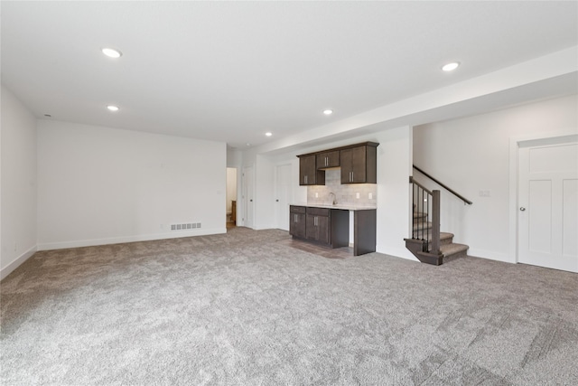 150 NW Hidden Knl, Waukee, IA 50263 - unfurnished living room featuring stairs, light colored carpet, recessed lighting, and bar