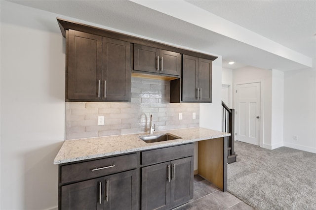 150 NW Hidden Knl, Waukee, IA 50263 - kitchen with dark brown cabinetry, light stone countertops, backsplash, and light carpet
