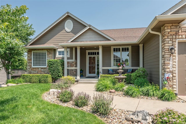 6725 NW 93rd St, Johnston, IA 50131 - view of front of property with stone siding, a front yard, covered porch, and a shingled roof