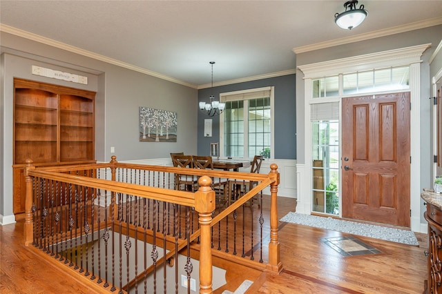 6725 NW 93rd St, Johnston, IA 50131 - foyer featuring wood finished floors, a chandelier, crown molding, wainscoting, and a decorative wall