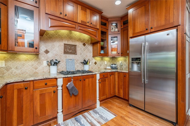 6725 NW 93rd St, Johnston, IA 50131 - kitchen with stainless steel appliances, brown cabinetry, light stone countertops, and light wood-style floors