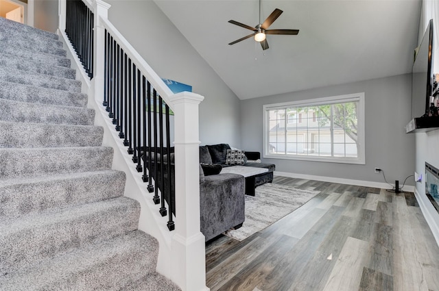 5462 Longview Ct Unit 1, Johnston, IA 50131 - living area featuring stairs, wood finished floors, a ceiling fan, a glass covered fireplace, and high vaulted ceiling