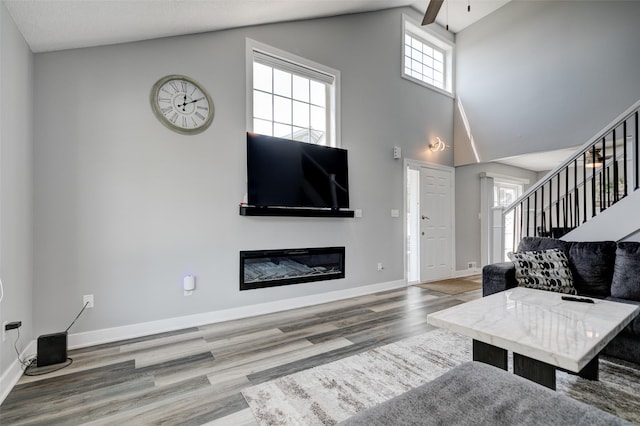 5462 Longview Ct Unit 1, Johnston, IA 50131 - living area with a glass covered fireplace, stairs, high vaulted ceiling, wood finished floors, and ceiling fan