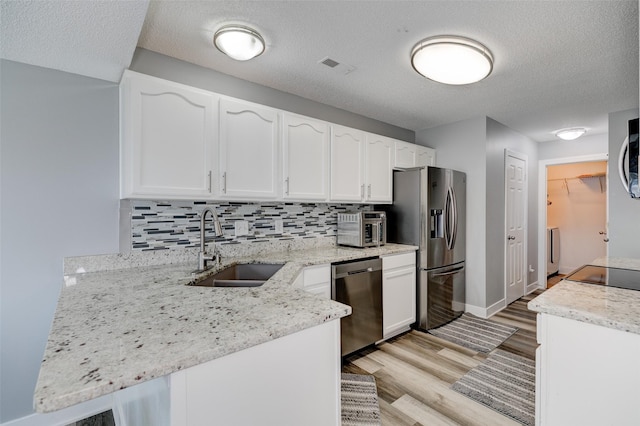 5462 Longview Ct Unit 1, Johnston, IA 50131 - kitchen featuring stainless steel appliances, white cabinets, a peninsula, light wood-style floors, and decorative backsplash