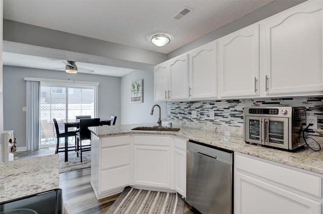 5462 Longview Ct Unit 1, Johnston, IA 50131 - kitchen featuring stainless steel dishwasher, wood finished floors, a peninsula, white cabinets, and decorative backsplash