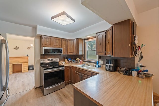 1543 S 16th Ave W, Newton, IA 50208 - kitchen with appliances with stainless steel finishes, light wood-style flooring, backsplash, light countertops, and brown cabinetry