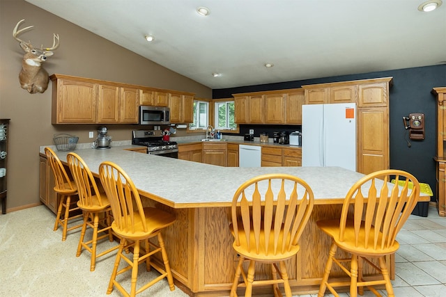 2626 SE 72nd St, Runnells, IA 50237 - kitchen featuring appliances with stainless steel finishes, light countertops, lofted ceiling, a breakfast bar, and a peninsula