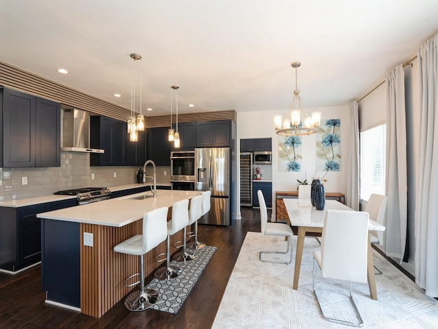 1010 Frederick Ave, Des Moines, IA 50315 - kitchen with appliances with stainless steel finishes, wall chimney exhaust hood, a chandelier, light countertops, and decorative backsplash