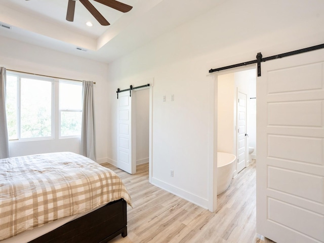 1010 Frederick Ave, Des Moines, IA 50315 - bedroom featuring a barn door, light wood-style floors, a tray ceiling, recessed lighting, and a ceiling fan