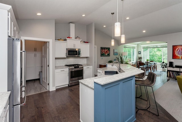 9180 Geanna Ct, West Des Moines, IA 50266 - kitchen featuring appliances with stainless steel finishes, a center island with sink, dark wood-style floors, vaulted ceiling, and a kitchen breakfast bar
