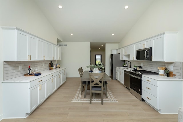 2004 Ammann Dr, Adel, IA 50003 - kitchen featuring stainless steel appliances, decorative backsplash, light countertops, white cabinetry, and recessed lighting